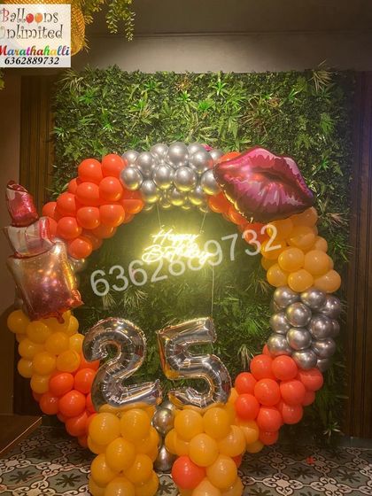 A fun and glamorous makeup themed 25th birthday, with a circular balloon arch against a green wall, accented with lipstick and lip foil balloons.