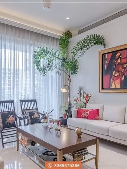 A closer look at the living area, with its comfortable white sofas, dark wood furniture, and bold, colorful artwork. The large windows and indoor plants add a touch of nature and light to the room.