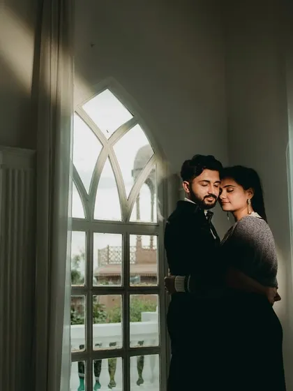 A quiet, contemplative moment by the window. The natural light creates soft shadows and highlights, resulting in a beautifully serene and intimate portrait of the couple.