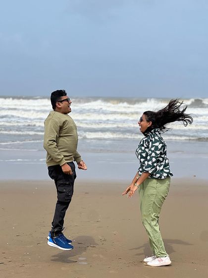 A fun, candid shot of a couple jumping on the beach.