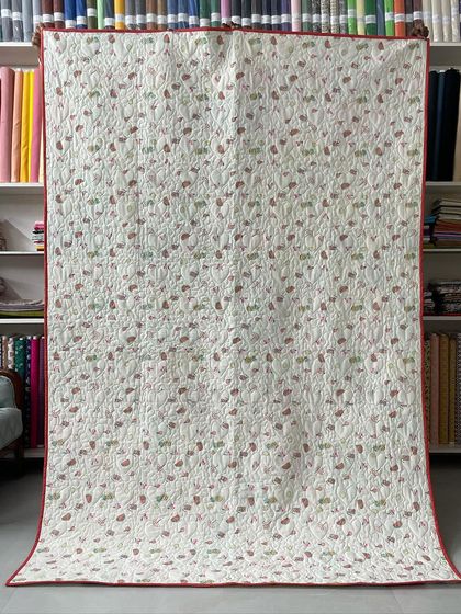 The back of the baby clothes memory quilt, showing a soft floral fabric and the heart-themed quilting pattern.