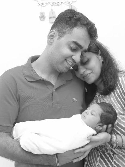 A peaceful moment with parents holding their sleeping newborn, captured in soft black and white.