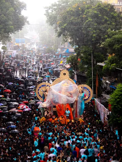 Even the rain doesn't stop the celebration. Here, the procession continues under a sea of umbrellas, showing the resilient spirit of Mumbai's festivals.