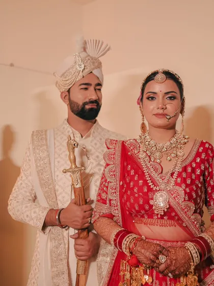 A classic portrait with a focus on the couple's coordinated outfits and regal bearing. The groom holds a sword, adding a traditional touch.