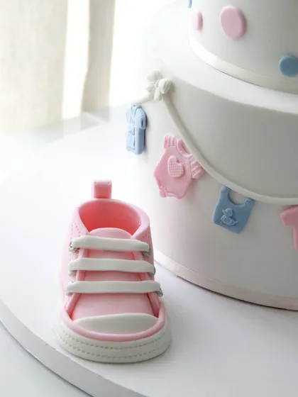 A close-up of the incredibly detailed, handcrafted pink fondant baby shoe.