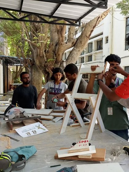 Students working together to assemble a folding chair. This kind of collaborative project is a big part of the workshop experience.