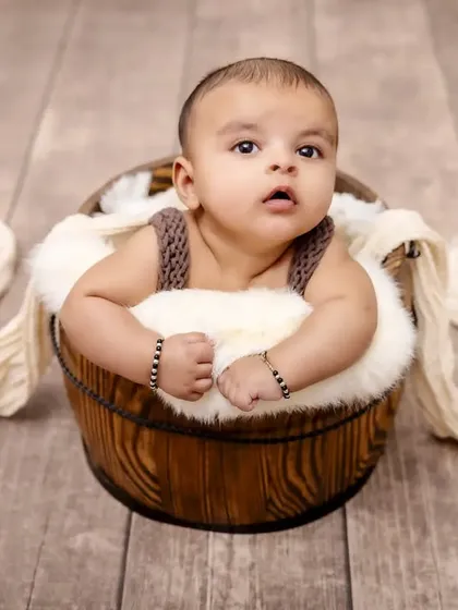 A cozy moment in a rustic wooden bucket. We use a variety of safe and comfortable props to create adorable portraits that highlight just how small your little one is.