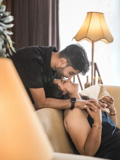 A close, intimate portrait capturing a gentle forehead kiss. The warm lamplight creates a cozy and romantic mood, perfect for highlighting tender emotions.