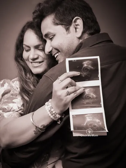 A treasured memory in sepia tones. This close-up shot captures the couple's joy as they look at their baby's first sonogram picture, creating a warm and nostalgic family portrait.