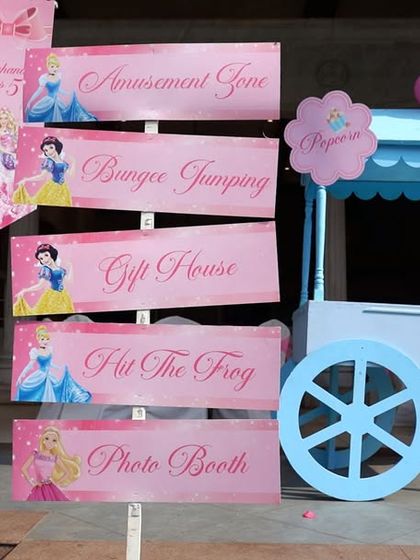 An elegant pink signpost for a Disney Princess party, guiding little royals to the 'Amusement Zone', 'Bungee Jumping', and 'Photo Booth'.