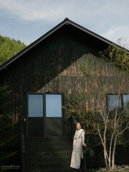 A modern architectural backdrop for a traditional bride. The contrast between the dark, minimalist house and the elegant saree creates a striking image.