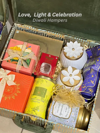 This premium Diwali hamper is packed in a stunning green and blue patterned trunk box. Inside, you'll find luxury chocolates, festive snacks, and beautiful floral-topped candle jars, blending tradition with modern luxury.