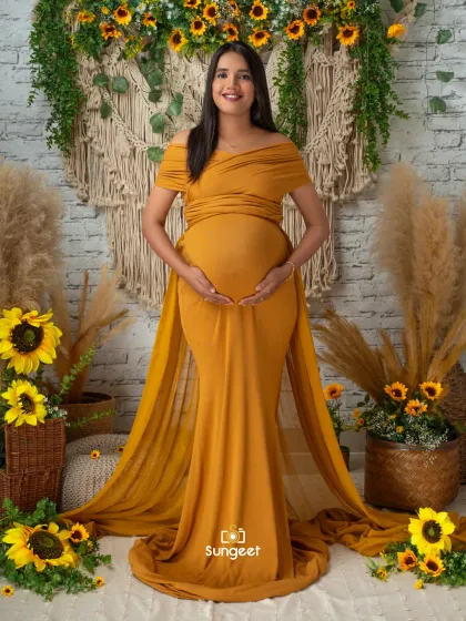 A classic solo portrait in a mustard yellow infinity gown. The boho-themed backdrop with sunflowers and pampas grass adds a warm, earthy feel.