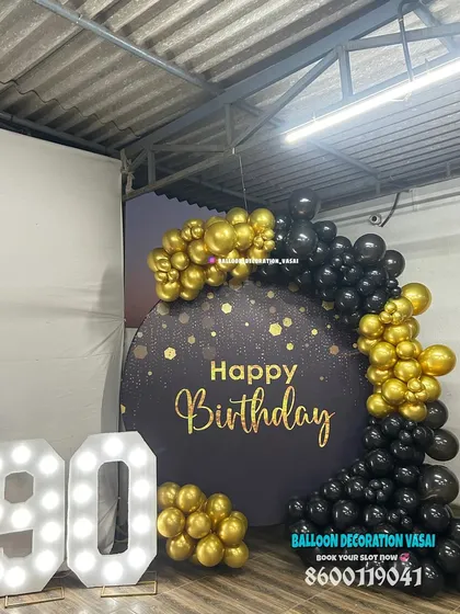 Celebrating a 90th birthday milestone in style. This sophisticated black and gold theme includes a custom "Happy Birthday" backdrop, a balloon garland, and large light-up marquee numbers to honor the special occasion.