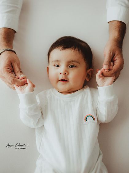 A parent's hands gently hold their baby's, creating a sense of security and love in this sweet 5-month milestone photo.