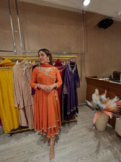 This orange angrakha-style suit is a timeless festive piece. The wrap-style kurta is flattering on many body shapes, and the color is warm and celebratory.
