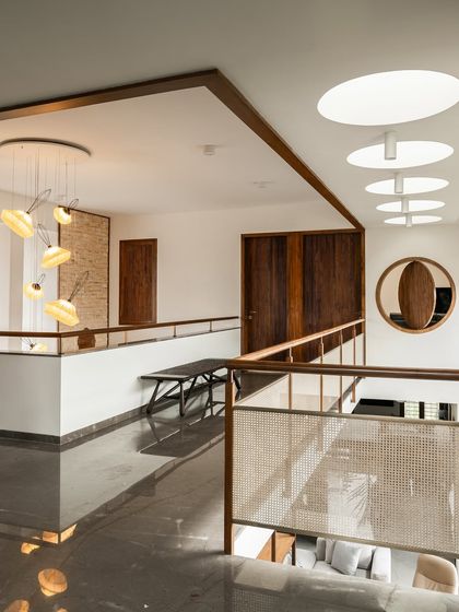 The upstairs gallery walkway benefits from multiple light sources, including circular skylights and a view down into the main living area. Polished flooring reflects the light, further brightening the space.