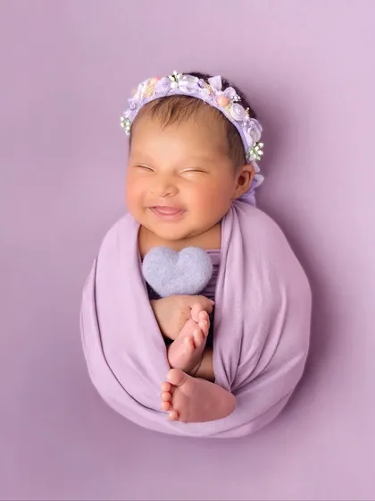 That sweet, sleepy smile says it all. In my posed newborn sessions, I use soft wraps and simple props against a vibrant backdrop to create beautiful, artful portraits of your little one's pure happiness.