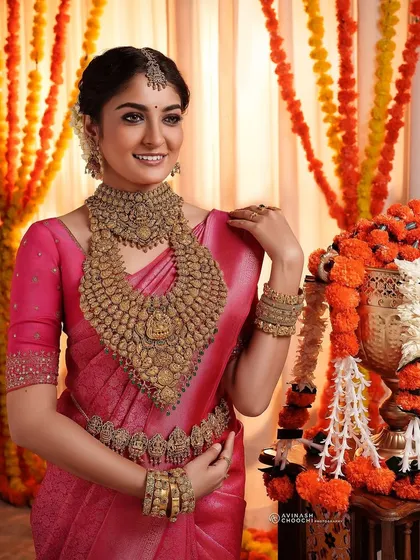 Another angle from the Rajakumari Gold bridal shoot. This profile view highlights the detailed hair adornments and the flawless finish of the makeup, creating a timeless bridal portrait.