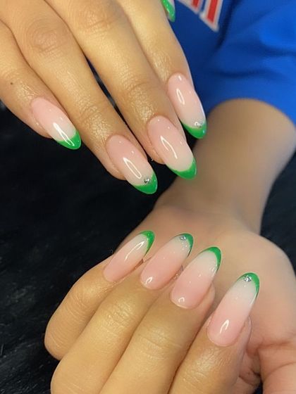 A full view of the striking neon green French manicure on long almond extensions.