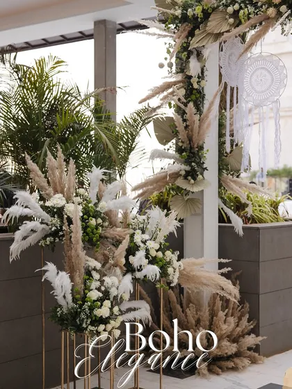 An example of boho-chic elegance. This decor uses pampas grass, dried palm leaves, and white florals to create a soft, textured, and natural aesthetic that is both rustic and luxurious.