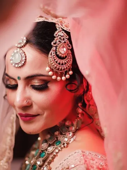A close-up of one of our brides, capturing the dreamy, romantic look we created. This artistic shot highlights the detailed eye makeup, flawless skin finish, and the perfect placement of traditional jewelry, all essential for a timeless bridal portrait.