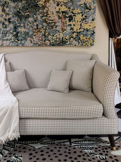 This custom-designed sofa is fully upholstered in a classic houndstooth fabric. Its elegant, curved arms and deep seat make it a comfortable and stylish centerpiece for any living room.