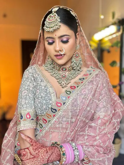 A close-up of the pastel pink lehenga look, focusing on the beautiful makeup and the intricate, heavy jewellery.