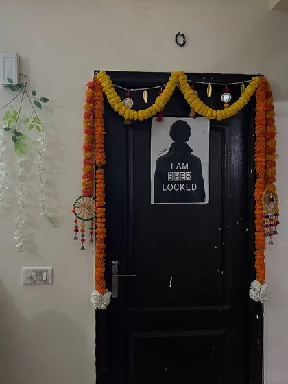 A simple door decoration with marigold garlands for a small home function.