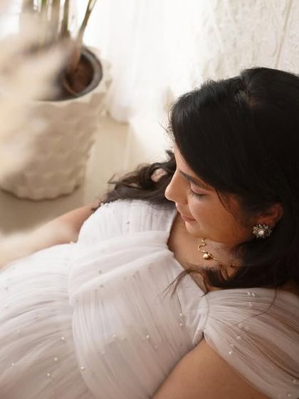 An artistic close-up shot through pampas grass, creating a soft and dreamy effect. This highlights the quiet, contemplative moments of pregnancy in a beautiful way.