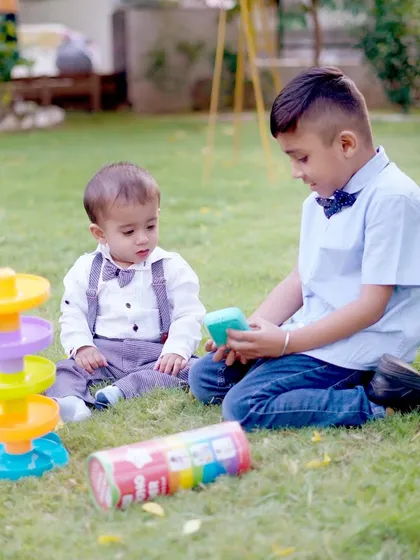 An older boy shares a toy with a toddler during a relaxed outdoor play session, a lovely example of sibling and friends photography.