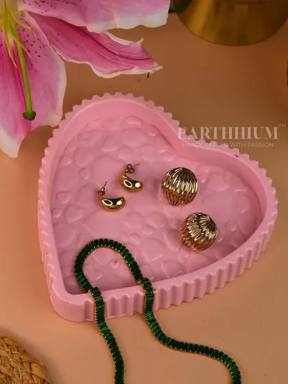 A heart-shaped Jesmonite tray in a soft pink. The beaded edge and floral-embossed interior make it a romantic and decorative piece for a vanity or dresser.