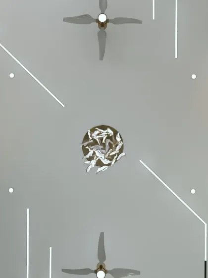 A view of a false ceiling with a unique, abstract lighting design and a sculptural chandelier. This shows how the "fifth wall" can be a work of art.