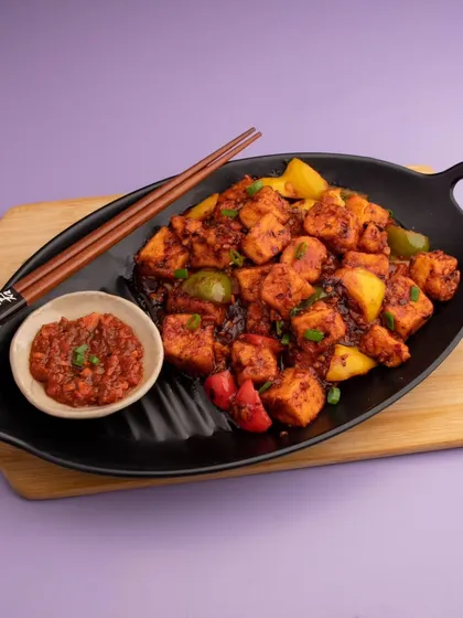 Spicy paneer dish shot for The Lantern Bar's online delivery menu. The dark plate and simple background ensure the food is the hero.