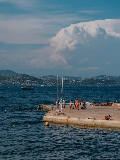 People enjoying a sunny day on a pier in St. Tropez. This candid scene captures the relaxed, leisurely atmosphere of the coastal town.