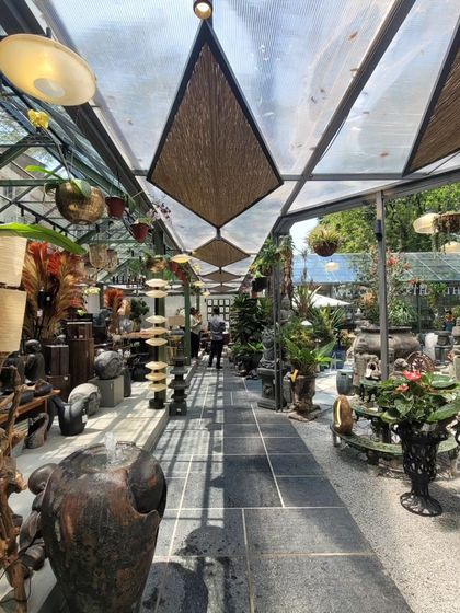 A long view through the central axis of the store, which is designed like a greenhouse gallery. The translucent roof with bamboo shades filters the sunlight, creating a perfect environment for both plants and shoppers.