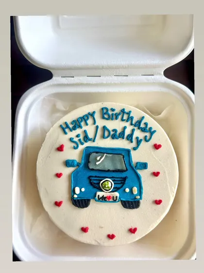 A closer look at the custom car bento cake, showing the details of the logo and headlights. Every little element is piped by hand with love.