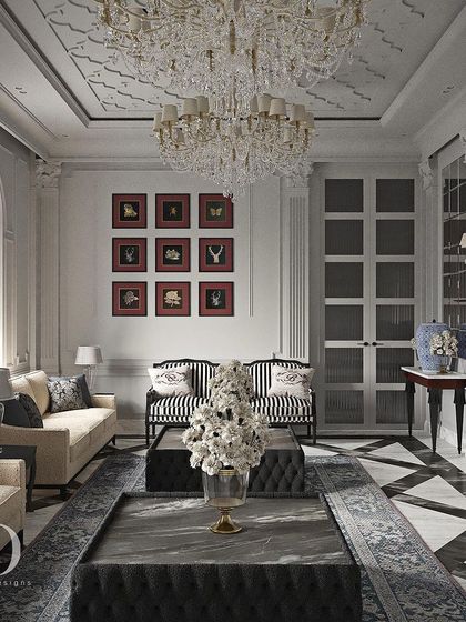 Another view of the black and white living room, showing a gallery wall of red-matted prints that adds a bold splash of color. The striped armchairs and symmetrical layout reflect a polished, Art Deco-influenced classicism.