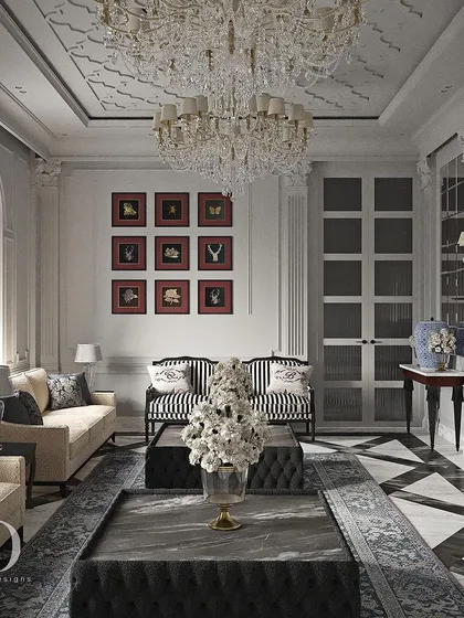 Another view of the black and white living room, showing a gallery wall of red-matted prints that adds a bold splash of color. The striped armchairs and symmetrical layout reflect a polished, Art Deco-influenced classicism.