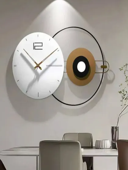 This wall clock is a study in modern minimalism. An offset white clock face is paired with a circular metal frame and a contrasting disc, creating an artistic and abstract composition that is both a clock and a piece of art.