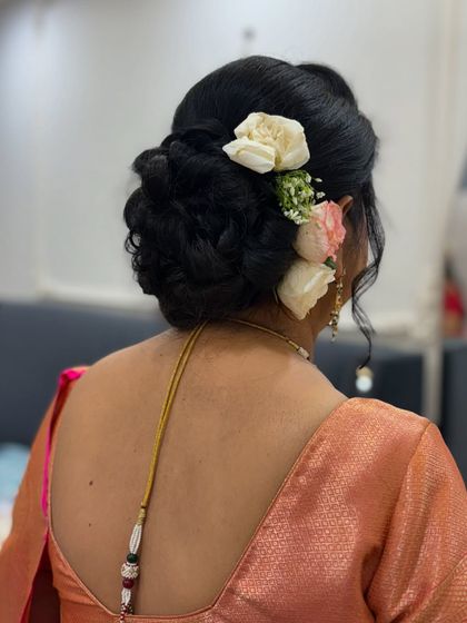 An elegant and classic low bun adorned with fresh roses. This timeless hairstyle is perfect for a saree look and keeps you comfortable all day.