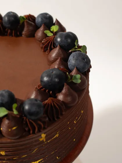 A close-up on the details. The smooth chocolate, perfectly piped swirls, and fresh blueberries make this cake a feast for the eyes and the palate.