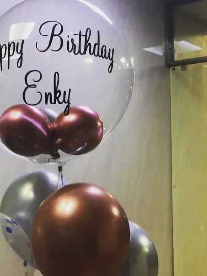 A personalized bubble balloon for Enky's birthday. The clear balloon with custom vinyl text is filled with smaller chrome balloons, creating a unique and modern gift.
