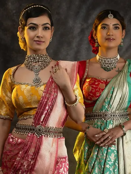 Two stunning models showcasing our custom blouses paired with traditional silk sarees, accessorized with beautiful silver jewelry for a festive look.