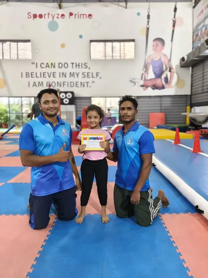 Two coaches celebrate with a young gymnast who has just earned her certificate. It's a team effort, and we are proud of them all.