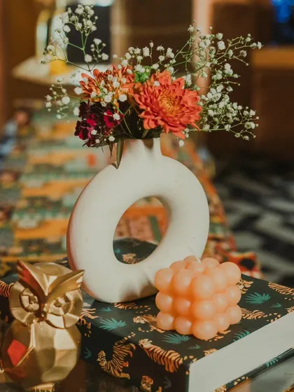 It's the little details that bring a theme to life. A modern white vase with fresh flowers, a quirky bubble candle, and a golden owl figurine create a stylish and personalized tabletop arrangement.