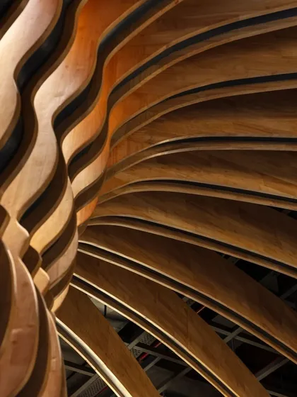 This close-up shot showcases the texture and form of the fluted columns at Nishtara. The interplay of light and shadow on the curved wood surfaces creates a dynamic and visually rich experience.