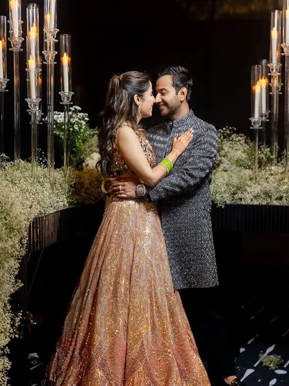 A quiet, romantic moment amidst the Sangeet celebrations. Her shimmer peach lehenga and his textured grey bandhgala are a perfect example of modern couple styling.