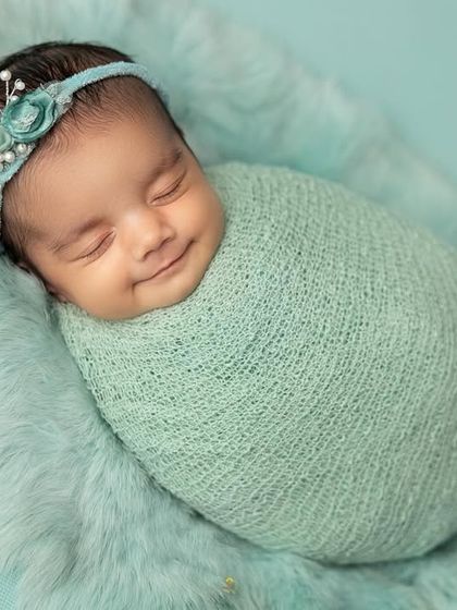 A heart-melting smile from a baby swaddled in a soft mint-green knit wrap. I use safe wrapping techniques to keep babies feeling secure and content, which often leads to these beautiful expressions.