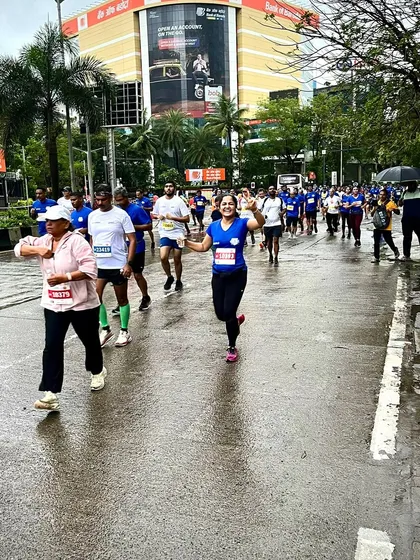 A runner enjoying the race, waving to the camera during the Mumbai Half Marathon.